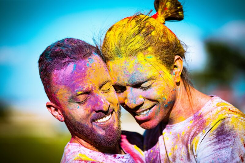 Two guys faces touching; painted with purple, yellow, blue