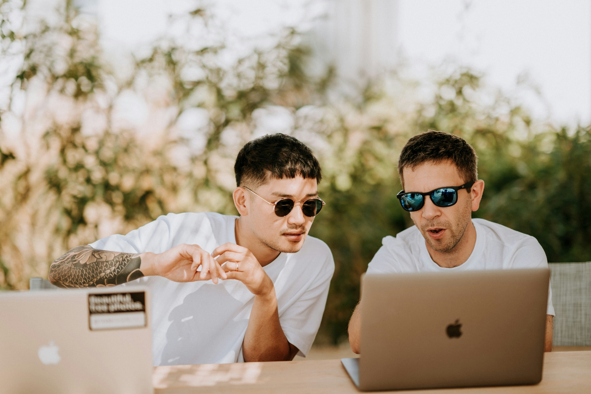 Two guys seated at a table looking at laptops