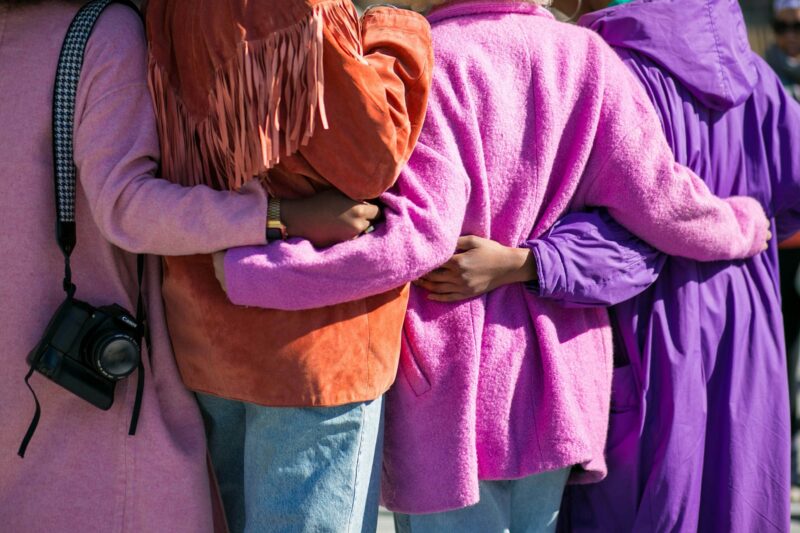 Shot of the backs of four people in purple/red coats